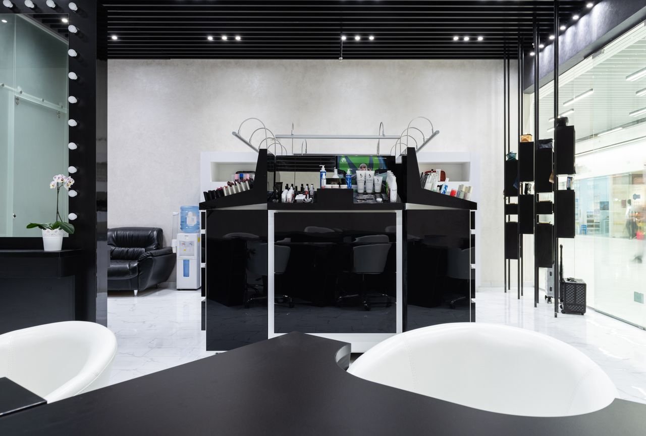 Modern beauty salon interior design in Dubai — reception area with warm neutral tones, marble counter and brass accents