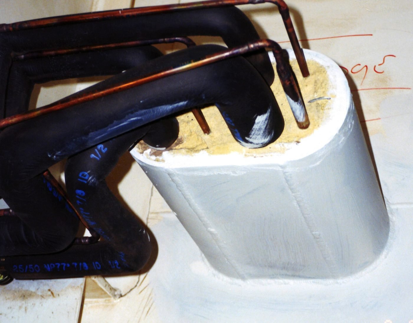 Firestop seal formed around insulated copper pipework passing through a rated wall penetration, showing the intumescent fill and the sleeve detail an inspector will look for