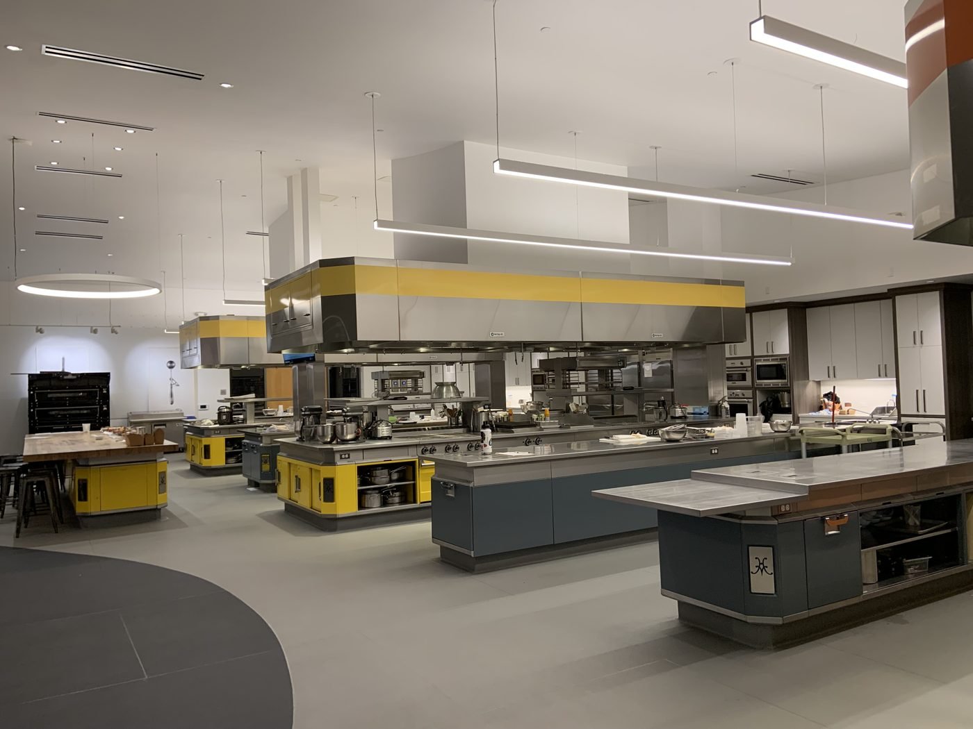 Cloud kitchen fit-out Dubai 2026 - open commercial production kitchen with stainless steel prep counters, separate cooking bays under extraction canopies and clear circulation aisles between stations
