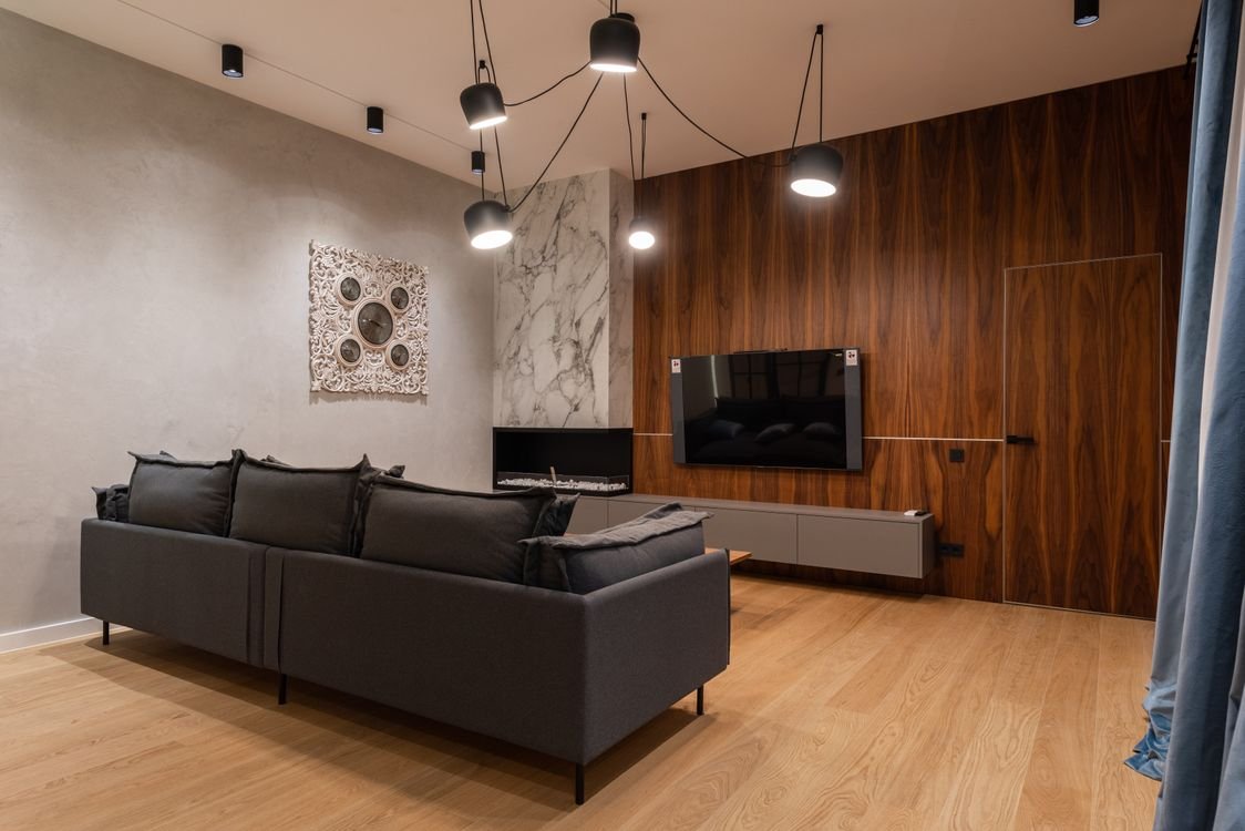 Feature wall design Dubai 2026 — modern living room with wood slat panel and marble stone cladding accent wall