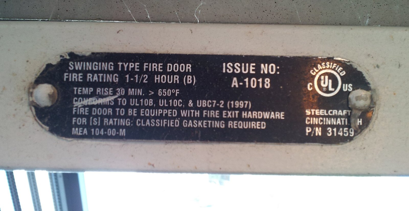Fire door certification label fixed to the hinge edge of a fire rated door leaf, showing the fire resistance rating and listing mark used to verify the door assembly at inspection