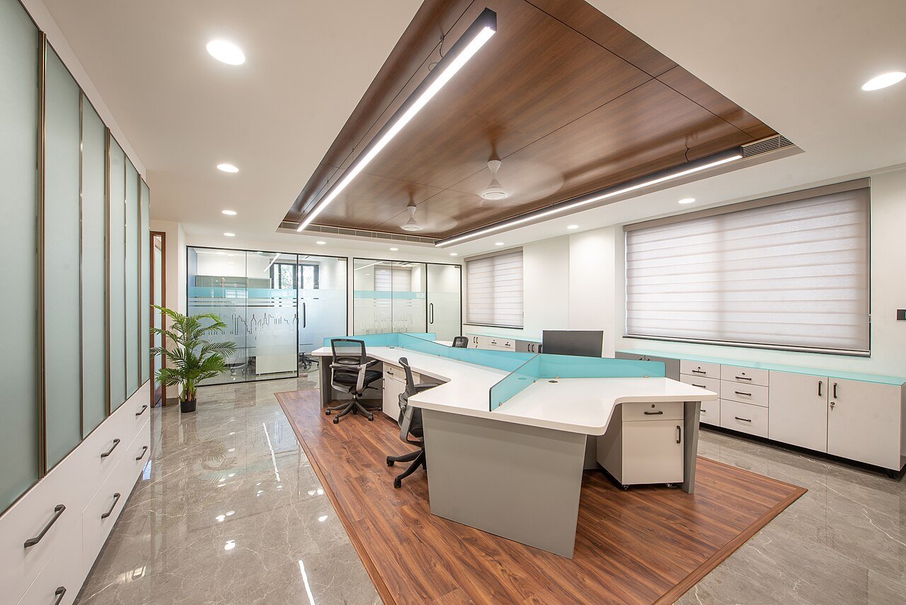 Fit-out quotation Dubai - completed office fit-out showing a timber ceiling raft, linear lighting, glazed partitions, joinery workstations and a marble-to-timber flooring transition, the trades a Bill of Quantities prices line by line