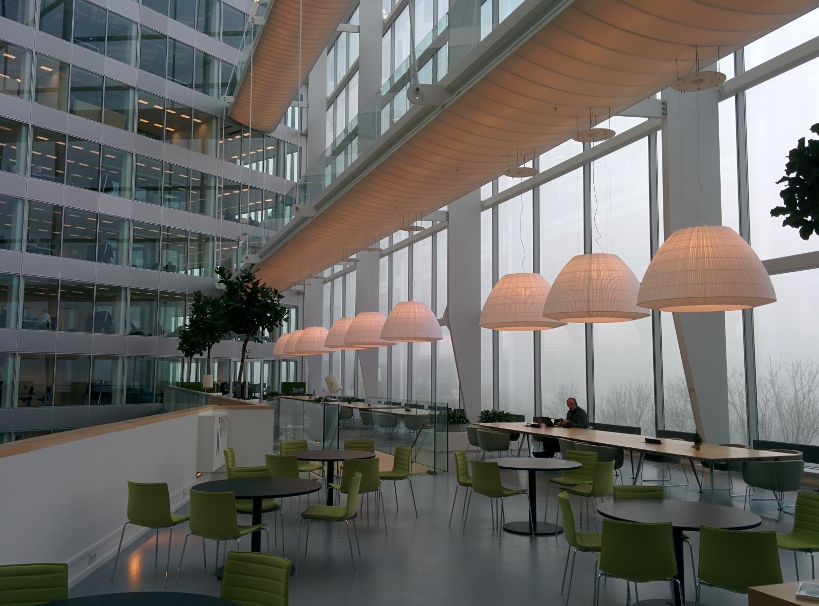 Internal glazed office partitions and a frameless glass balustrade in a multi-storey commercial atrium, showing full-height glass partition walls to individual offices