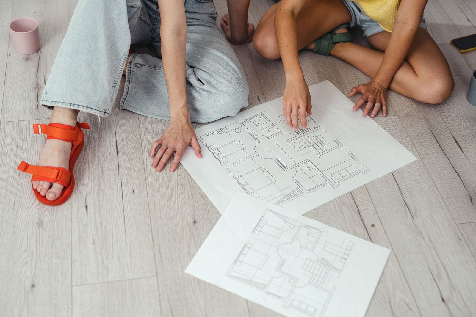 Two professionals reviewing floor plans for home renovation project management in Dubai, with drawings spread across a planning table