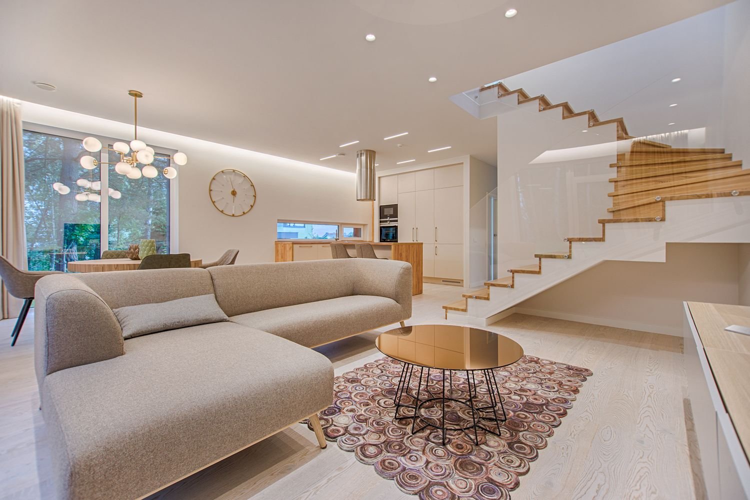 Modern open-plan luxury apartment interior in Dubai 2026 — living room with gold pendant light, neutral tones and bespoke joinery