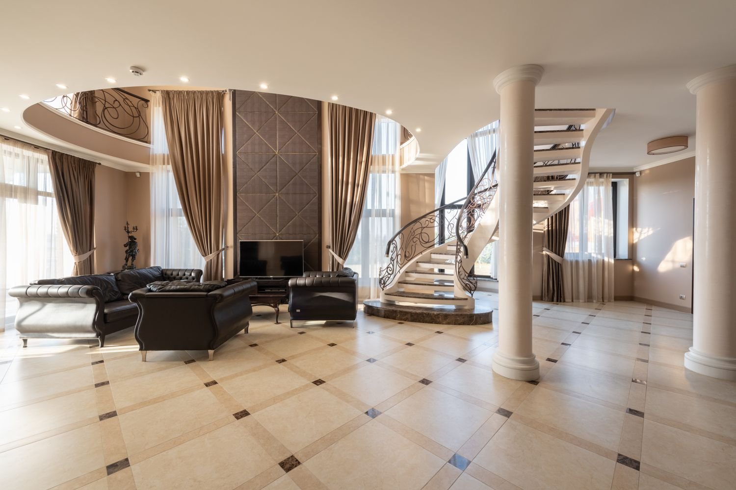 Curved luxury villa staircase in Dubai with wrought iron balustrade and marble treads, 2026 interior design