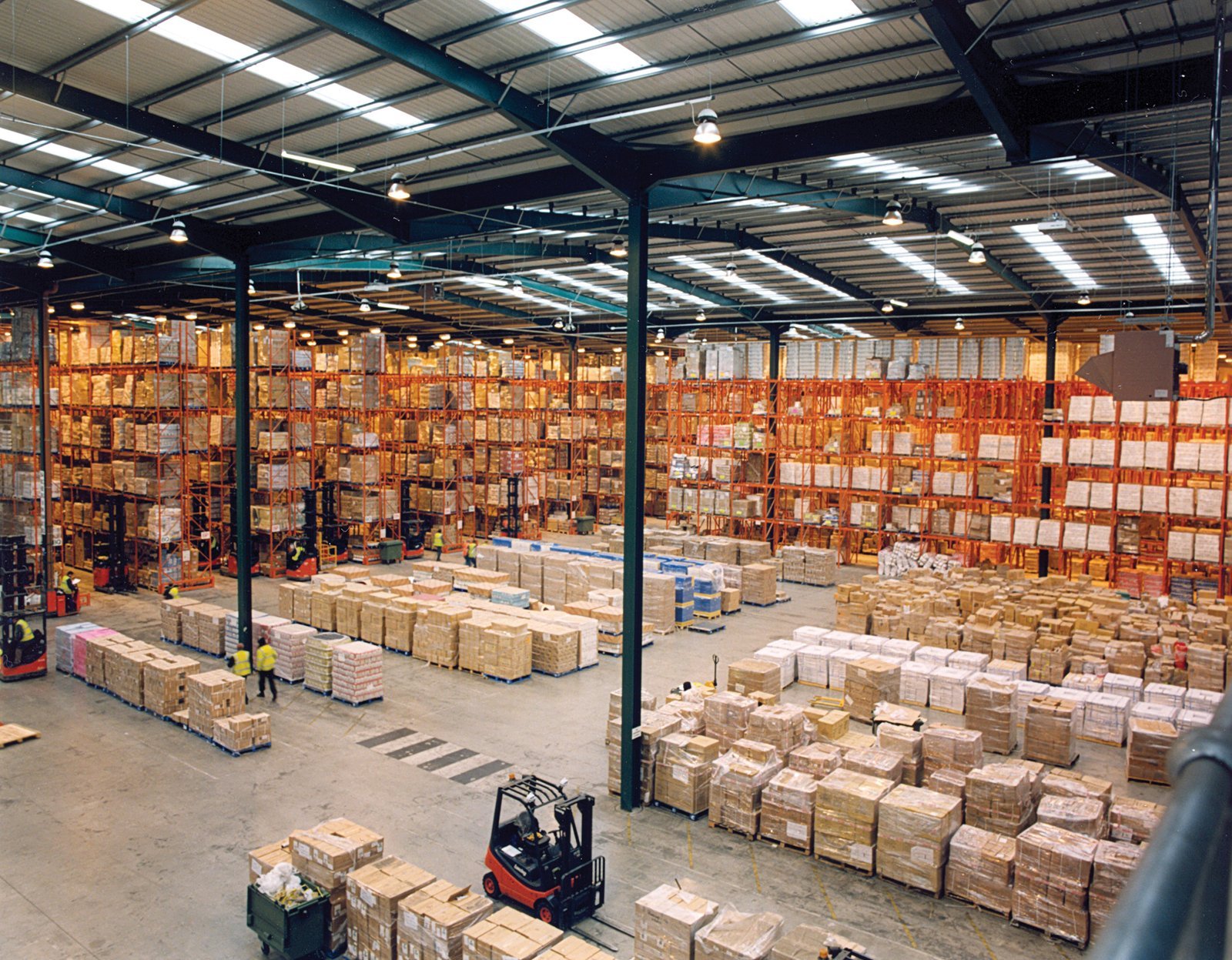 Warehouse mezzanine floor Dubai - high-bay pallet racking in a modern warehouse interior, the storage arrangement that determines sprinkler deflector clearance and in-rack sprinkler requirements under a mezzanine deck